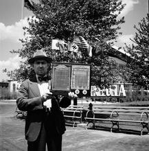 [Man holding universal calendar near the Venezuela pavilion, Government Zone, New York World's Fair.]