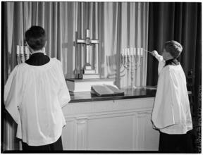 [Altar boys lighting candles.]