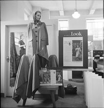 Bloomingdale's [Display in Bloomingdale's featuring a mannequin with a coat and "As Seen in LOOK Magazine" posters surrounding the display.]