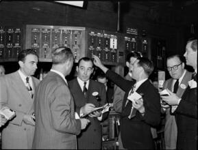 Stock Exchange [Men looking at stock prices on the floor of the stock exchange.]