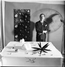Salvador Dali: Rugs [Salvador Dali standing in front of a rug he designed near a table with objects.]