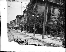 [Unidentified street scene, row of clapboard buildings with businesses on the ground floor]
