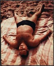 Untitled [Man sleeping on the beach at Coney Island.]