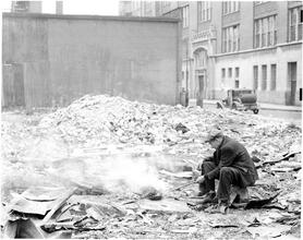 [Man cooking in junk lot.]