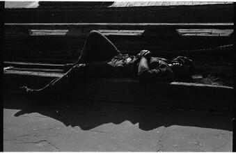 [Destitute man sleeping on pier.]