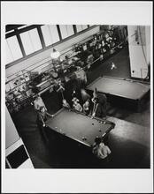 [Men playing pool as children watch on Ellis Island.]