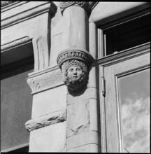 [Detail of face sculpture on unidentified building.]