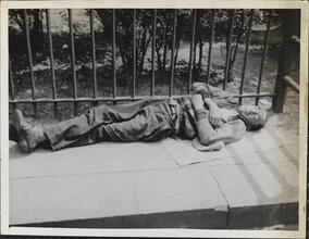 [Destitute man sleeping on pavement.]