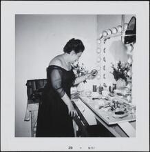[Berta Gersten in a dressing room, looking at a photo of her late husband, Irwin H. Fenn.]