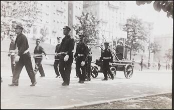 [Fire fighters pulling an old fire engine.]
