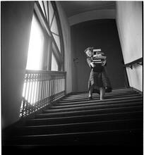 Columbia University [Student carrying a stack of books down stairs.]