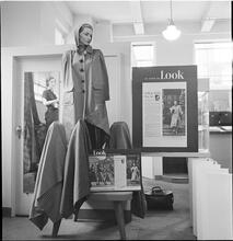 Bloomingdale's [Display in Bloomingdale's featuring a mannequin with a coat and "As Seen in LOOK Magazine" posters surrounding the display.]