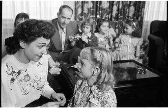 Deaf Children [Teacher helping child with her hearing aid.]
