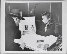 [Pavelle Laboratories. Man and woman looking at prints and slides.]