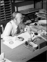 [Man writing at a desk.]