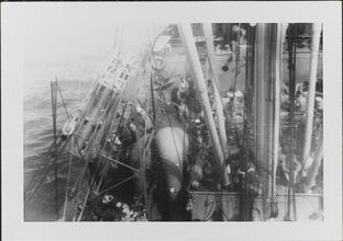 [View of ship's mast and deck with crew members.]