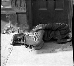 [Destitute man sleeping on doorstep.]
