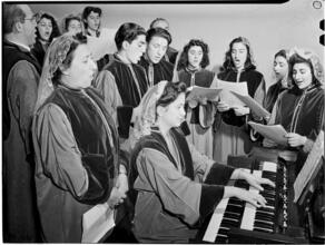[Choir practicing around an organ.]