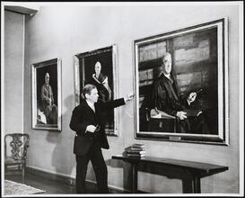 [Man standing in front of a portrait painting.]