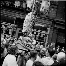 [Statue of Jesus Christ, covered with money, being carried in a religious procession.]