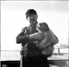 Waterfront. [Man holding a dog.]