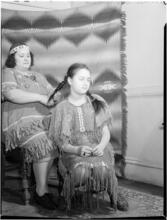 [Woman braiding a girl's hair.]