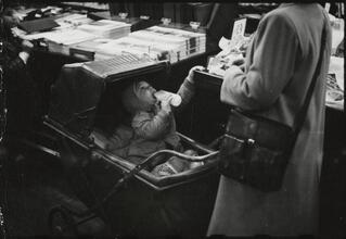 The 5 and 10 [Child in a stroller drinking from a bottle at Woolworth's.]