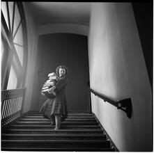 Columbia University [Women carrying a stack of books down a flight of stairs.]