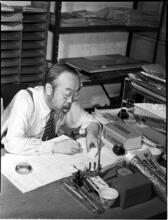 [Man writing at desk.]