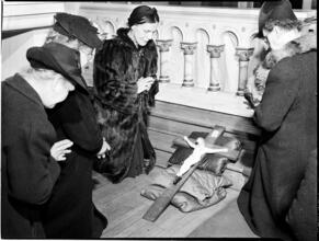 [Women praying over a crucifix.]