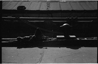 [Destitute man sleeping on pier.]