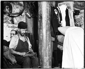 Shoemaker working in a house in the yard of 219 Broome Street, which the landlord built when the sanitary police put him out of the basement. Clatterpole sticks up through his house. Rent $12 a month.