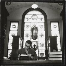 Columbia University [Man reading in a library.]