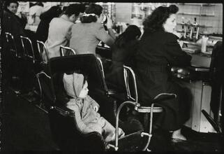 The 5 and 10 [Child in a stroller at the lunch counter in Woolworth's.]