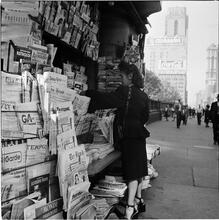 Newsstand [People browsing through magazine racks at a busy sidewalk newsstand.]