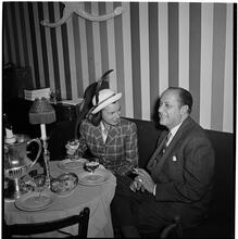 Champagne Cholly Book Party [Man and woman talking at a table.]