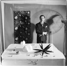 Salvador Dali: Rugs [Salvador Dali standing in front of a rug he designed near a table with objects.]