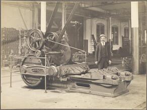 [Man standing next to an early bulldozer in a Brooklyn Rapid Transit machinery shop.]