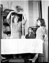 [Woman praying as her children watch.]
