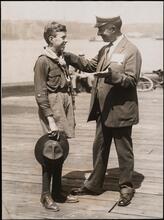 [Al Smith talking to a boy in a scouting uniform.]