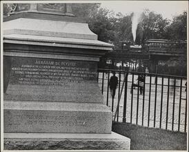 [Base and inscription for Abraham de Peyster Statue, steam locomotive on elevated railroad in the background]