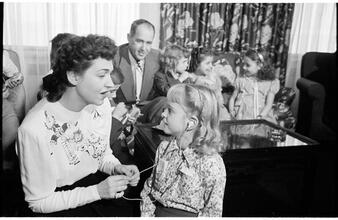 Deaf Children [Teacher helping child with her hearing aid.]