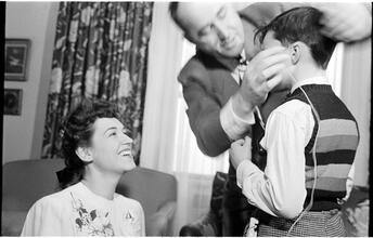 Deaf Children [Two teachers helping a child with his hearing aid.]