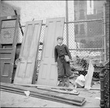 School Boy and Old Doors against Wire Fence
