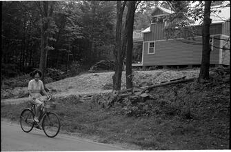 [Unidentified woman riding bicycle.]
