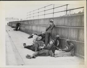 [Destitute men laying on pavement.]