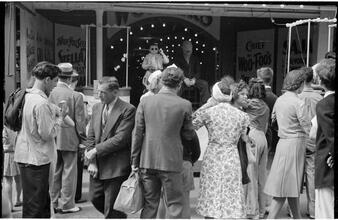 [Crowd watching sideshow performers from midway.]