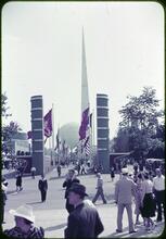 [The Trylon and Perisphere in the distance of a flag-lined walkway.]