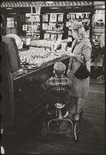 The 5 and 10 [Woman shopping with a boy riding a tricycle in Woolworth's.]