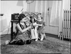 [Girls playing with a doll.]